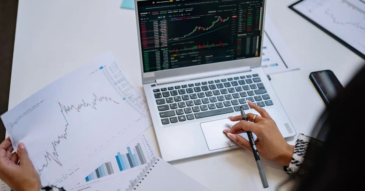 A detailed look at business analysis with a laptop displaying graphs and financial charts on a table.