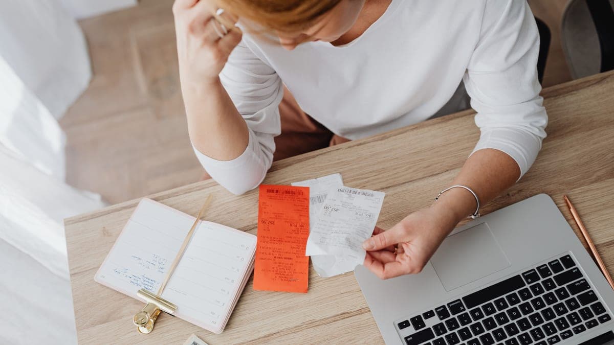 A person reading a payslip at a desk and checking the tax code on it