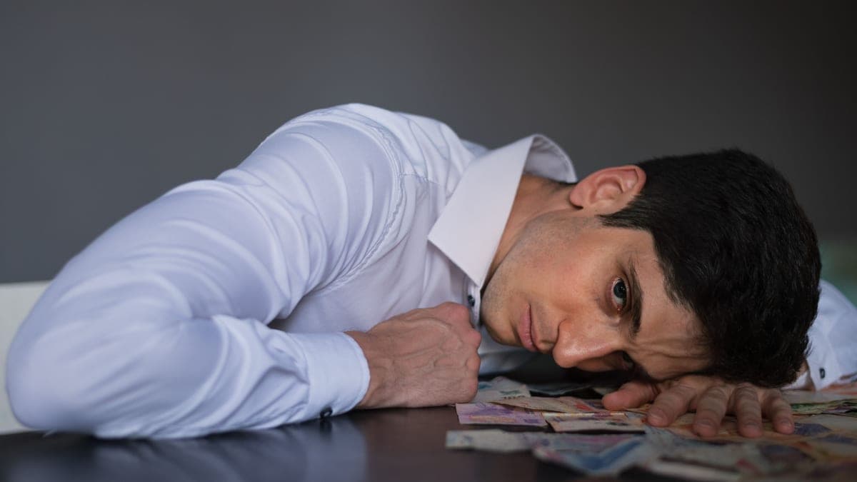 A man at a kitchen table opening an HMRC letter with a laptop and paperwork beside him