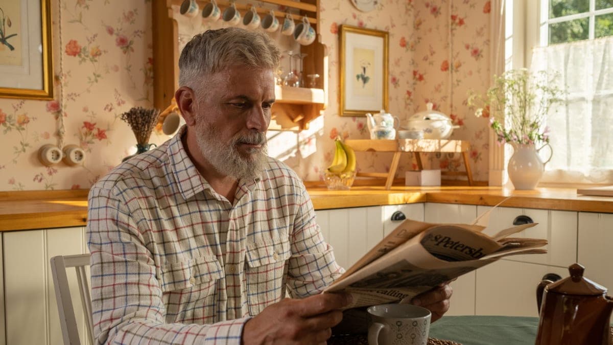 A man at a kitchen table checking an HMRC letter against his bank statements